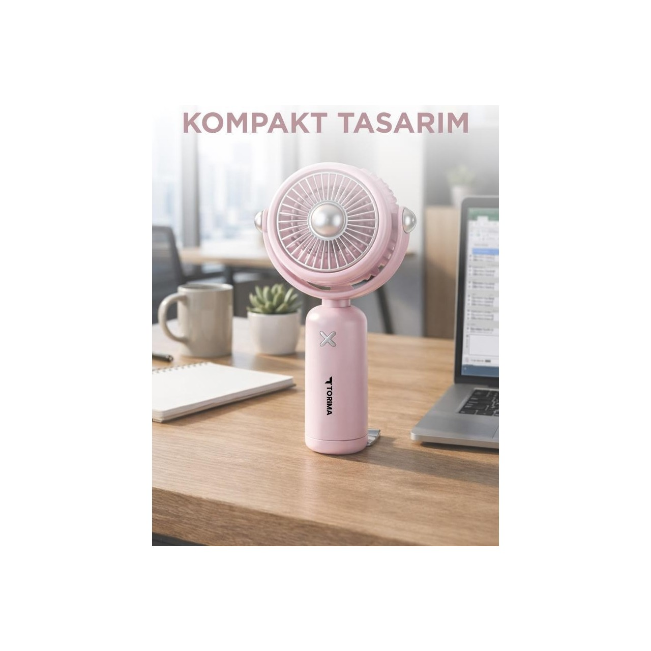Pembe elde taşınabilir fan, dizüstü bilgisayarın yanında ahşap bir masada duruyor.