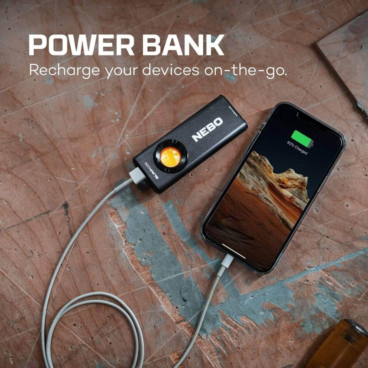 Une banque d'alimentation Nebo noire charge un smartphone sur une surface en bois rustique.