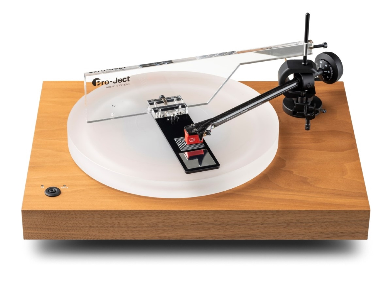 Gramofon z drewnianą podstawą, białym talerzem, ramieniem i przezroczystą osłoną przeciwpyłową.