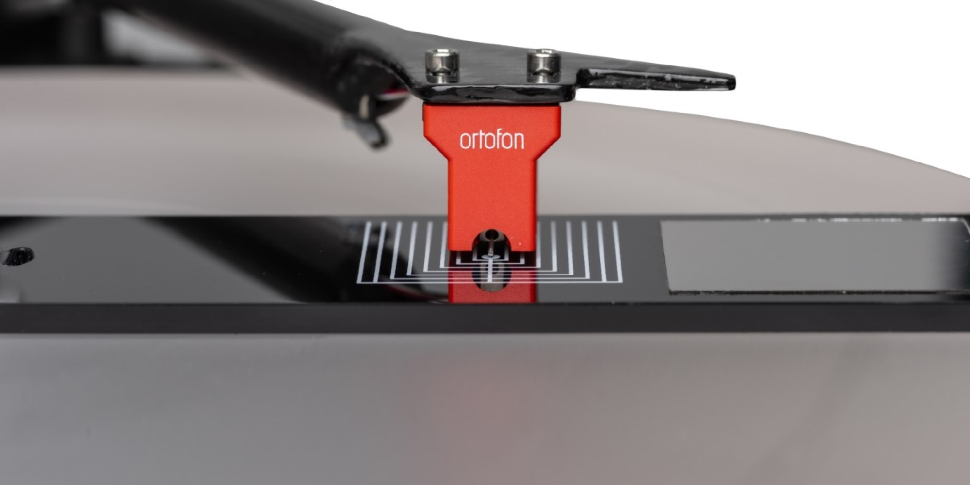 Czerwona wkładka Ortofon na gramofonie z igłą i skalą.