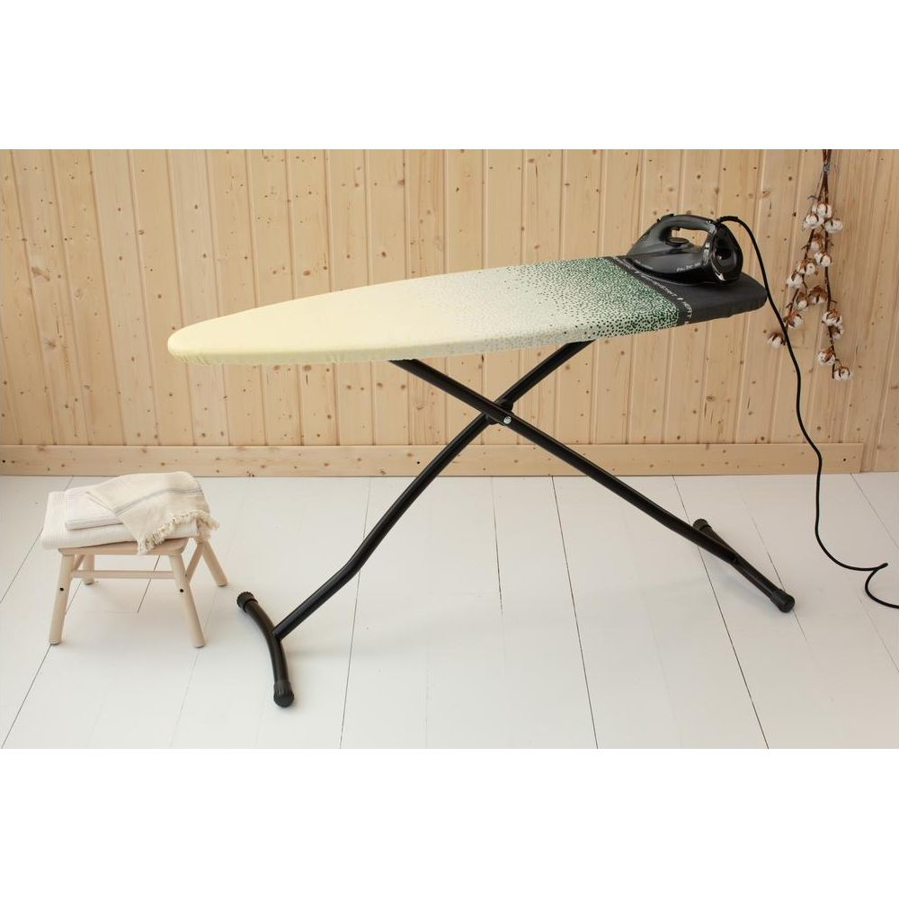 Une planche à repasser avec un fer à repasser et des serviettes pliées sur un tabouret.