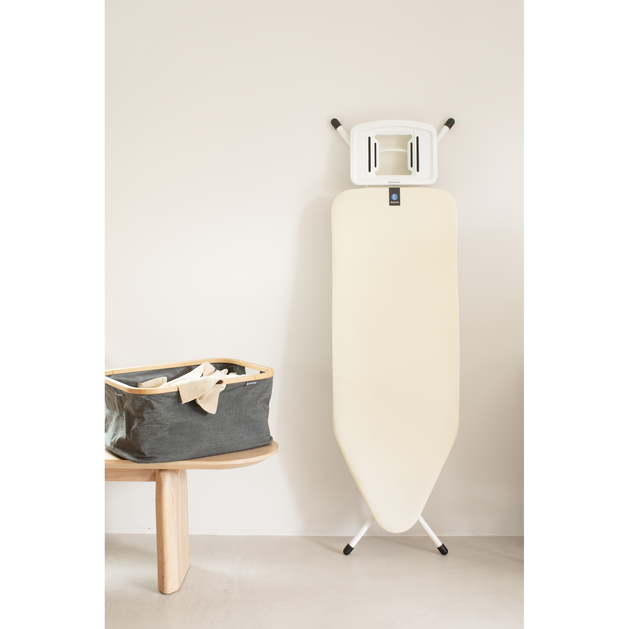 Une planche à repasser se trouve à côté d'un panier à linge sur une table en bois.
