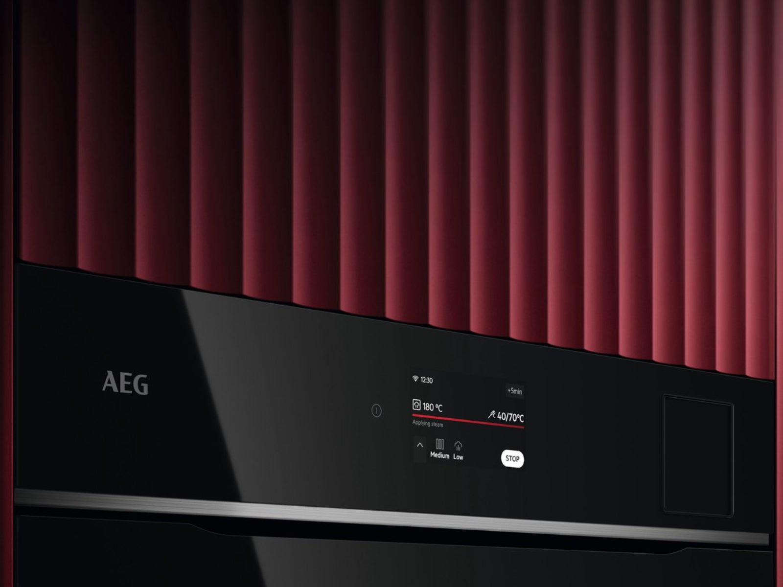 Un four AEG avec texture côtelée rouge et écran numérique affichant 180°C.