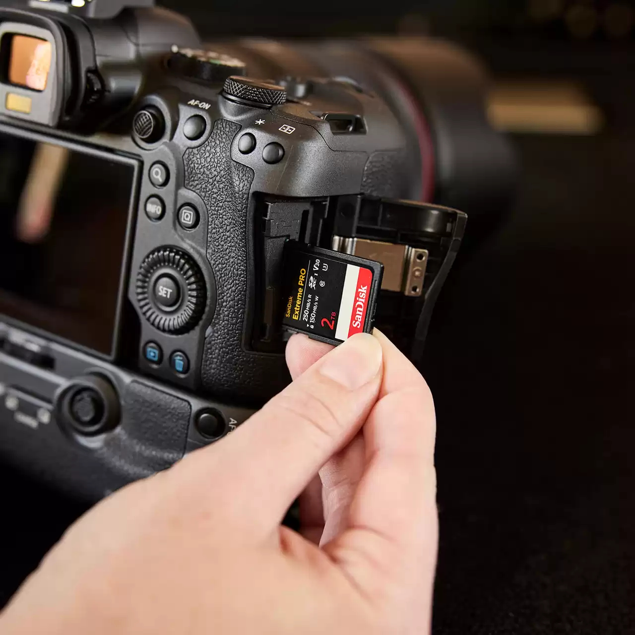Una mano inserisce una scheda di memoria SanDisk da 2TB in una fotocamera digitale.