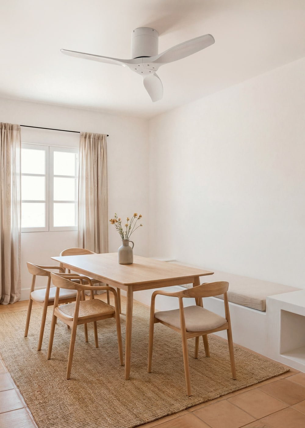 Una mesa de comedor de madera con cuatro sillas, un jarrón con flores y un ventilador de techo.