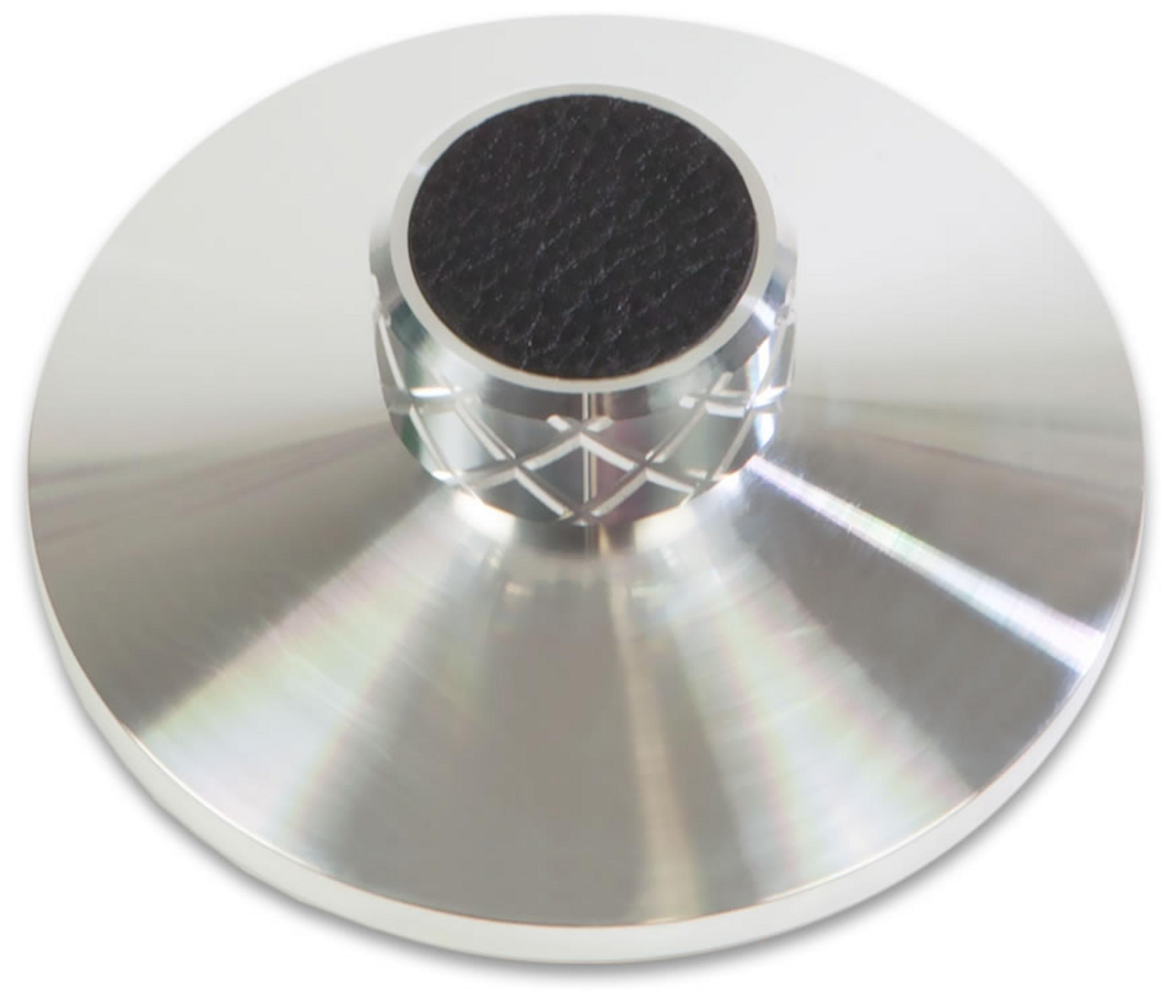 A silver turntable puck with black rubber grip and a textured pattern.