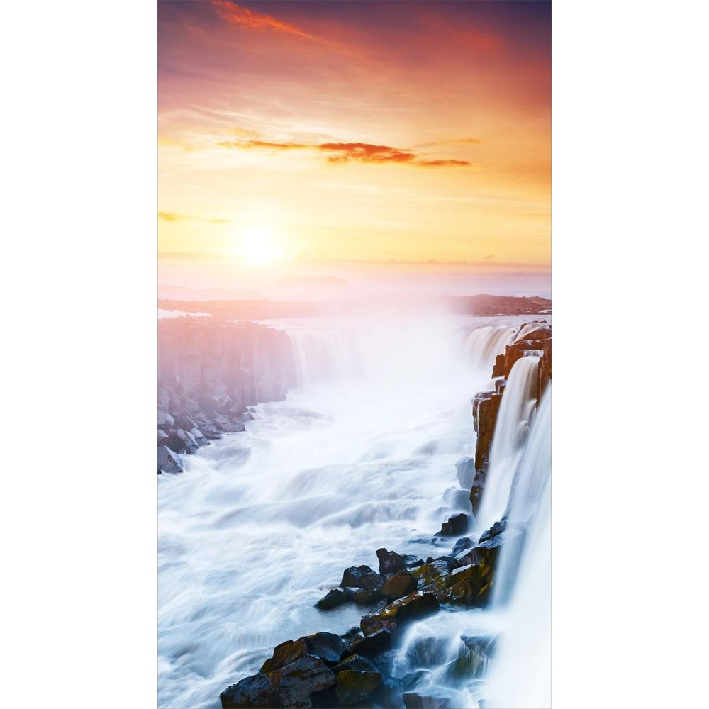 Una cascata scende su rocce in un fiume, all'alba con cielo drammatico.