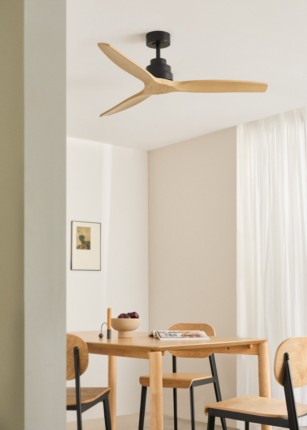 Un comedor moderno con mesa de madera, sillas y ventilador de techo negro.