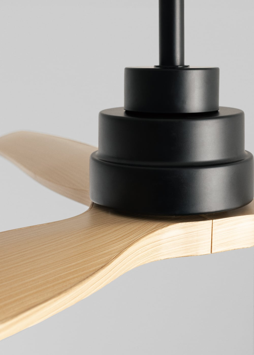 Primer plano de un motor de ventilador de techo negro con aspas de madera.