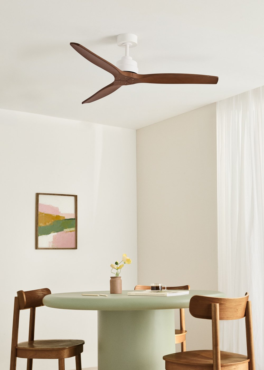 Un comedor moderno con ventilador de techo blanco, arte abstracto y mesa verde claro.
