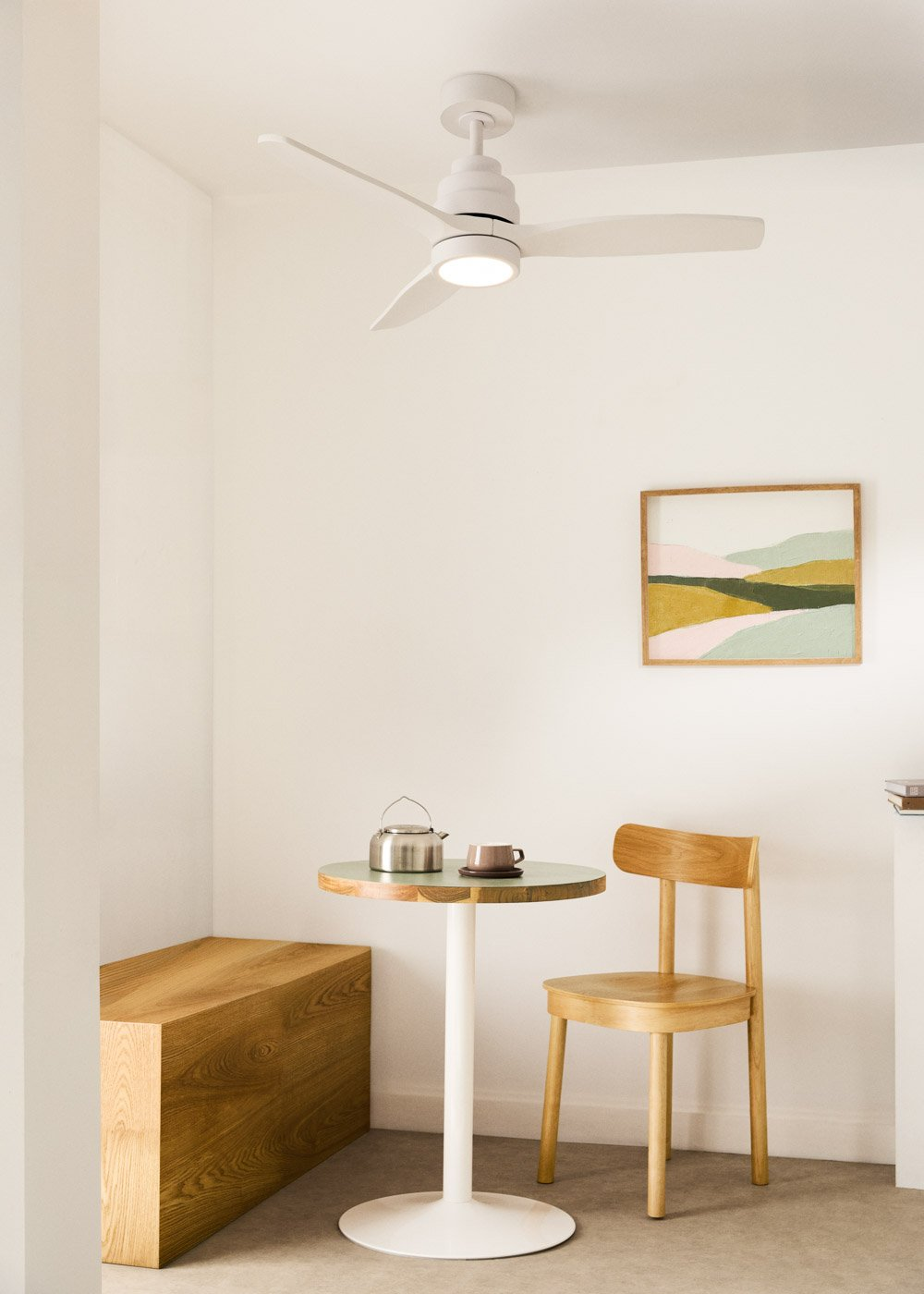 Una habitación con banco de madera, mesa, silla, ventilador de techo y arte mural.
