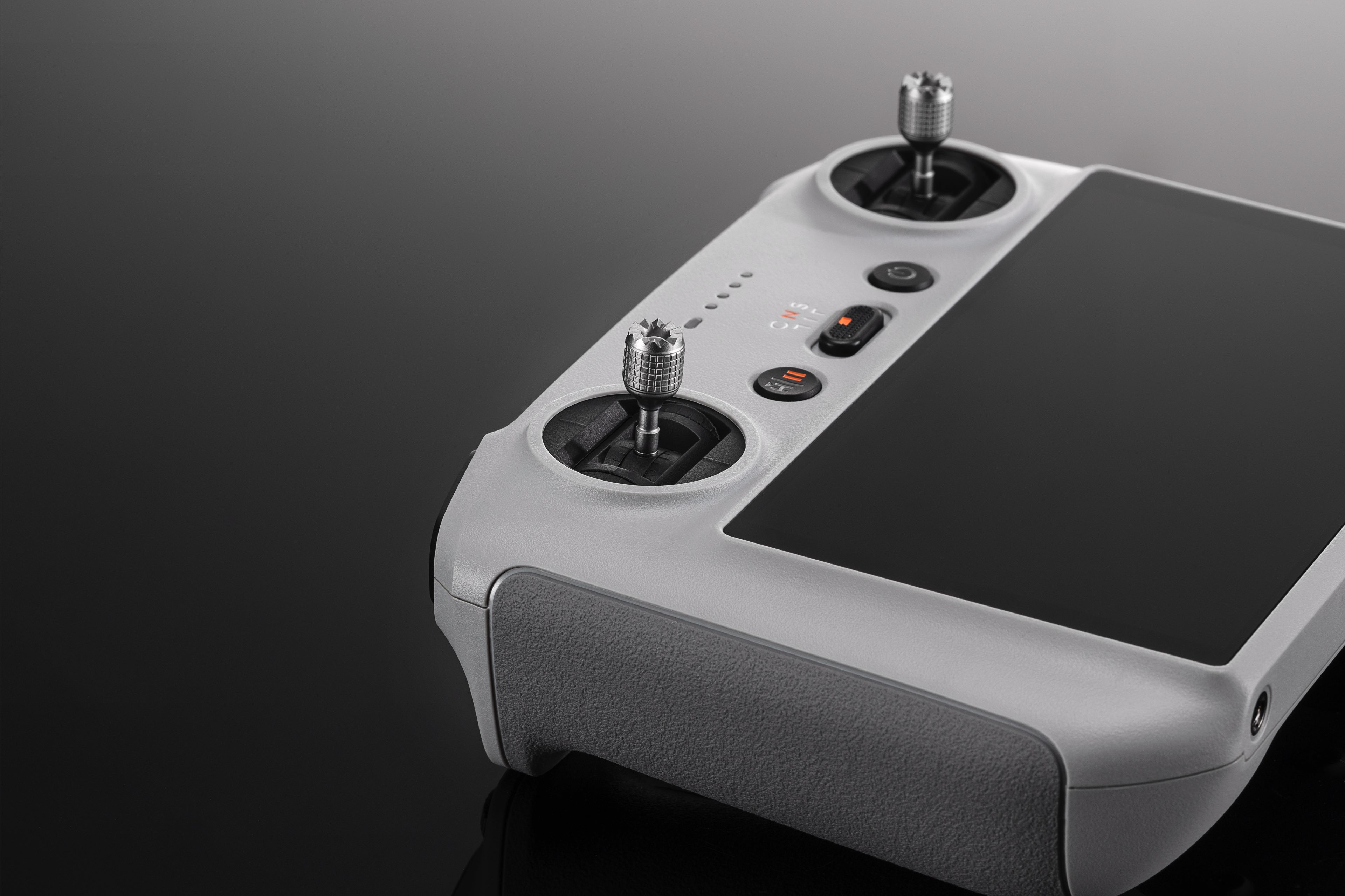 Grauer Drohnen-Controller mit zwei Joysticks und einem schwarzen Bildschirm.