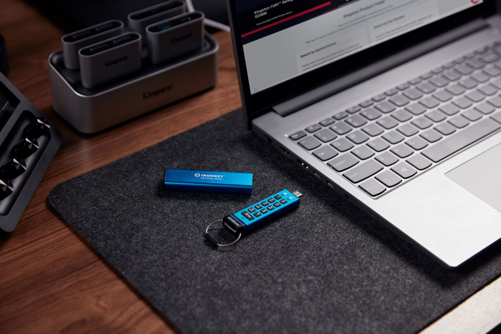 Zwei blaue USB-Sticks liegen neben einem Laptop auf einer grauen Matte.