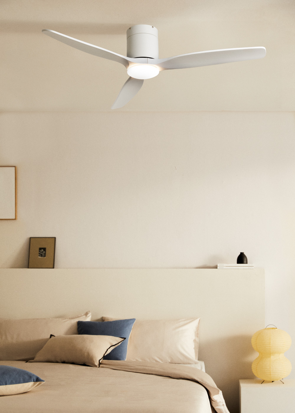Un ventilador de techo blanco con luz sobre una cama con almohadas.