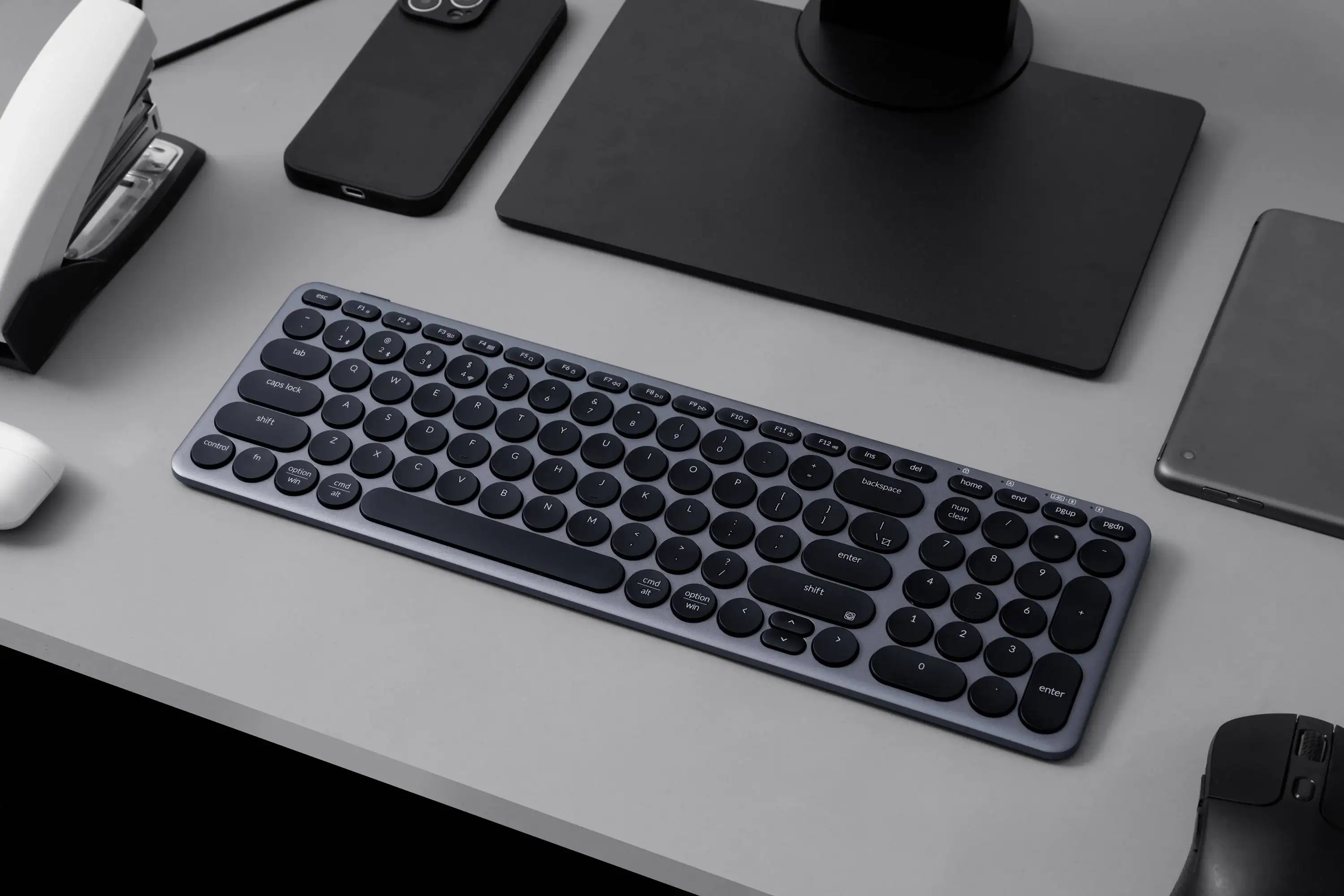 Biurko z klawiaturą, myszą, telefonem, dziurkaczem i podstawą monitora.