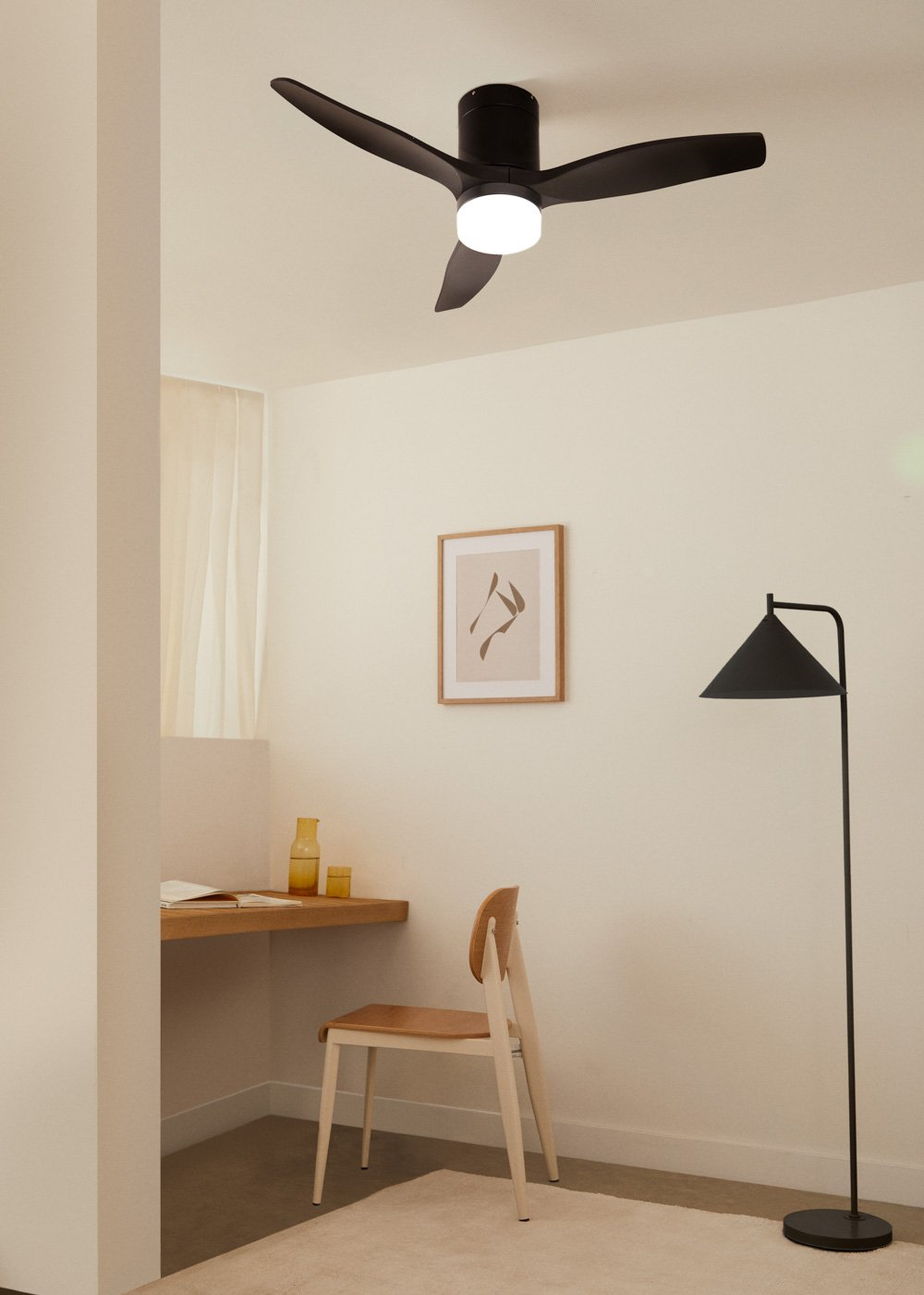 Un ventilador de techo oscuro con luz sobre un escritorio con silla.