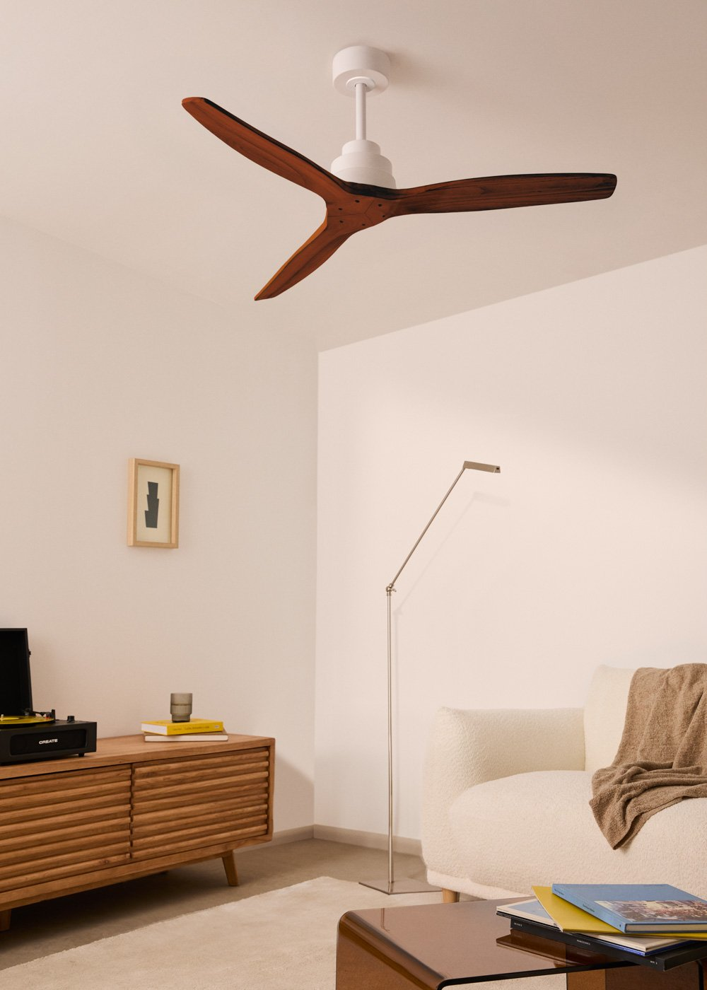 Una sala de estar moderna con ventilador de techo blanco, mueble de madera y sofá blanco.