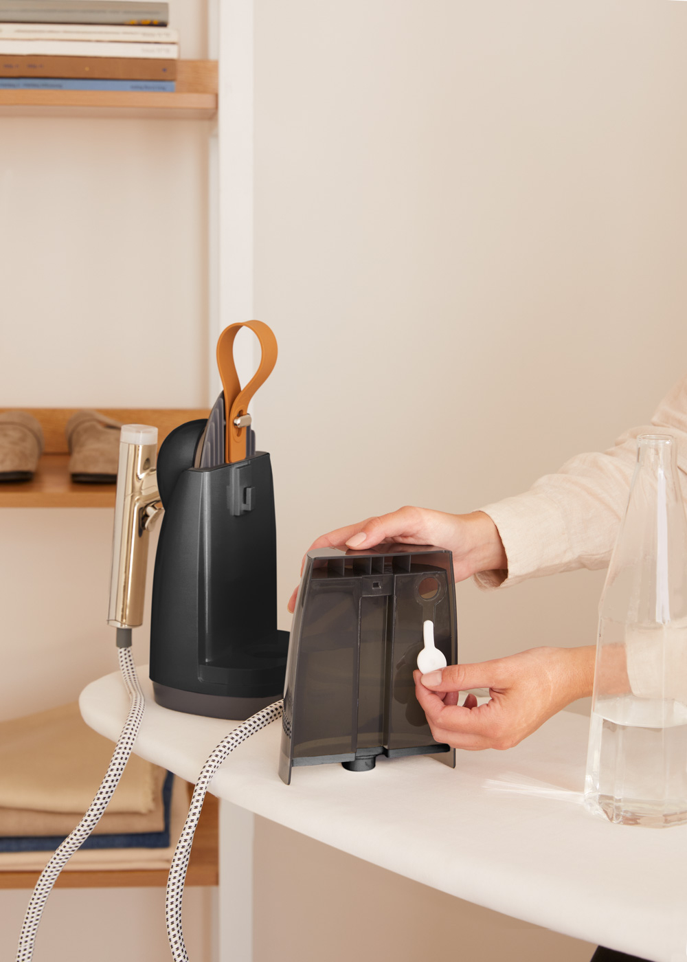 Una persona está llenando el depósito de agua de una plancha de vapor.