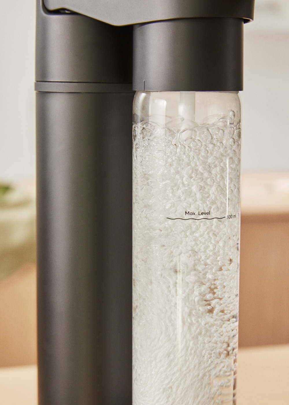 Una máquina de soda con una botella de vidrio llena de agua con gas.