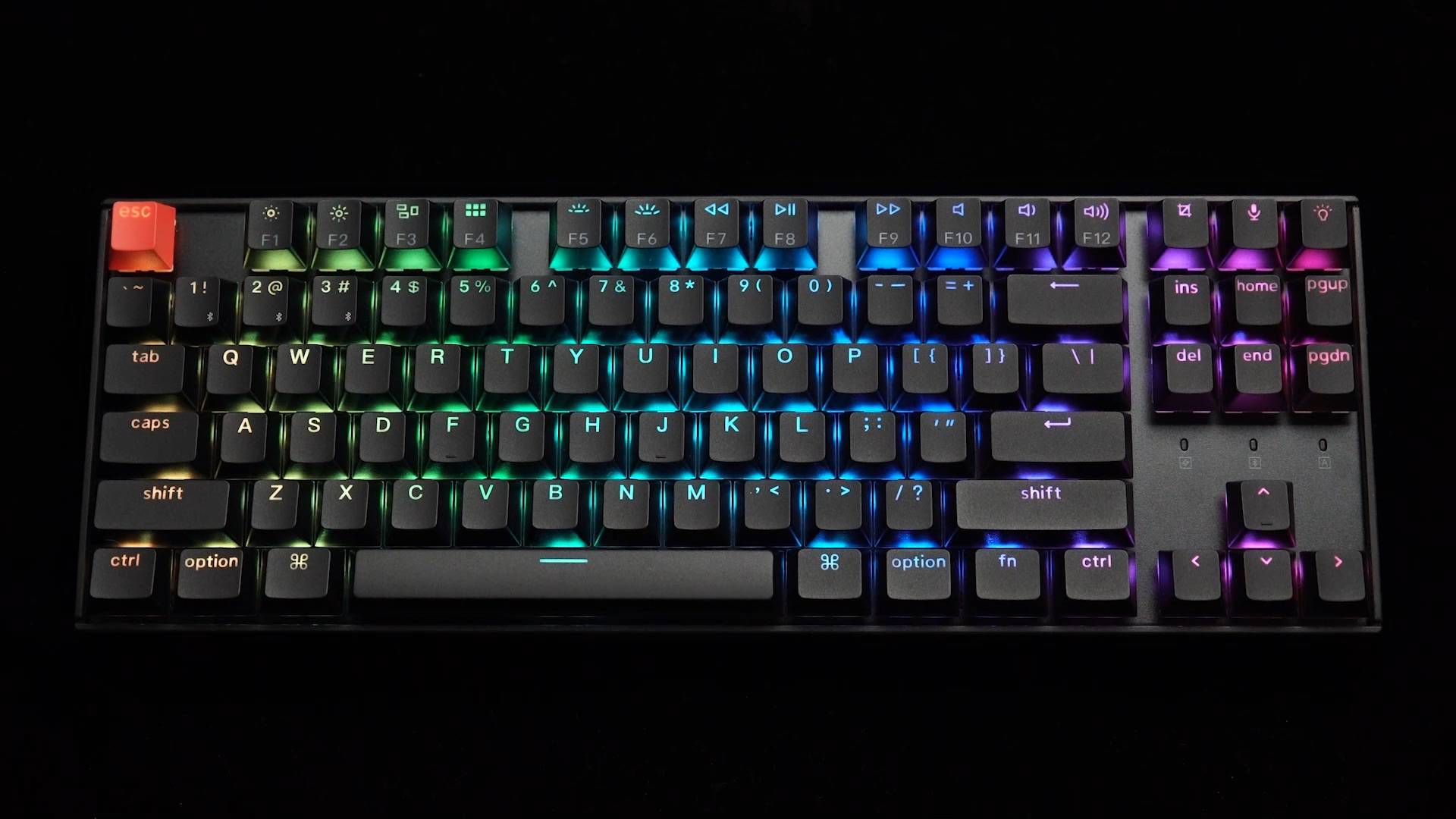 Czarna klawiatura z podświetlanymi klawiszami RGB na czarnym tle.