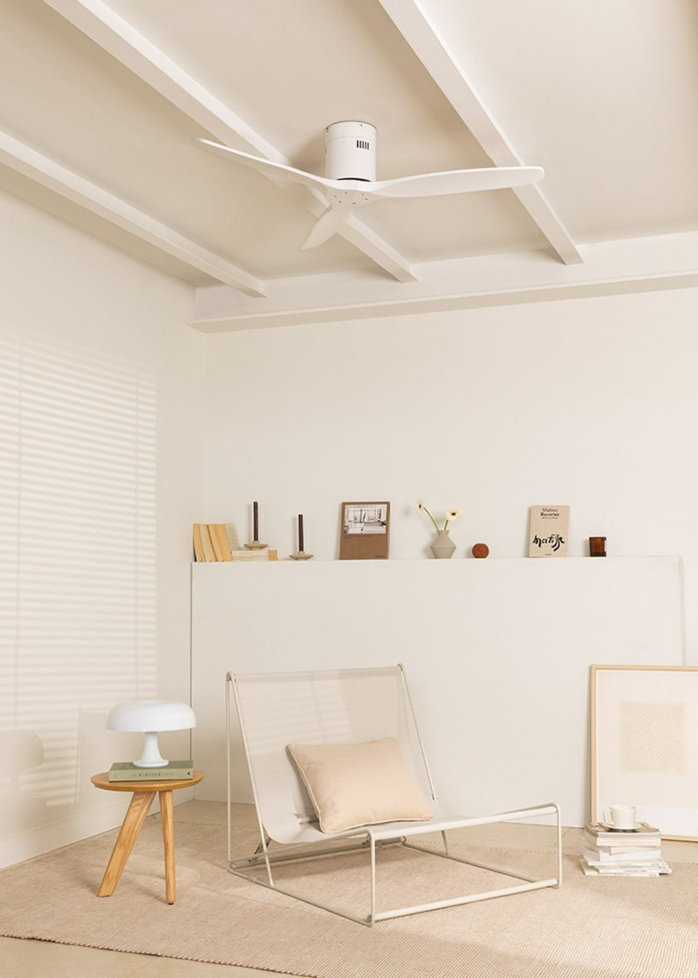Una sala de estar luminosa con ventilador de techo, silla, mesa y estante.