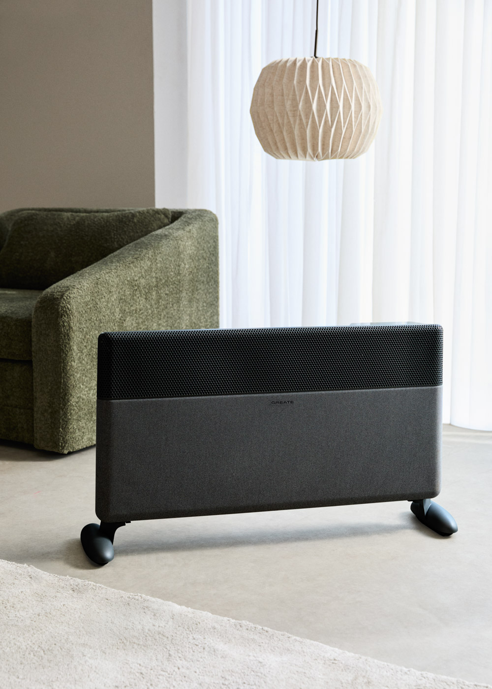 Un calentador oscuro con ruedas está en una sala de estar junto a un sillón verde.