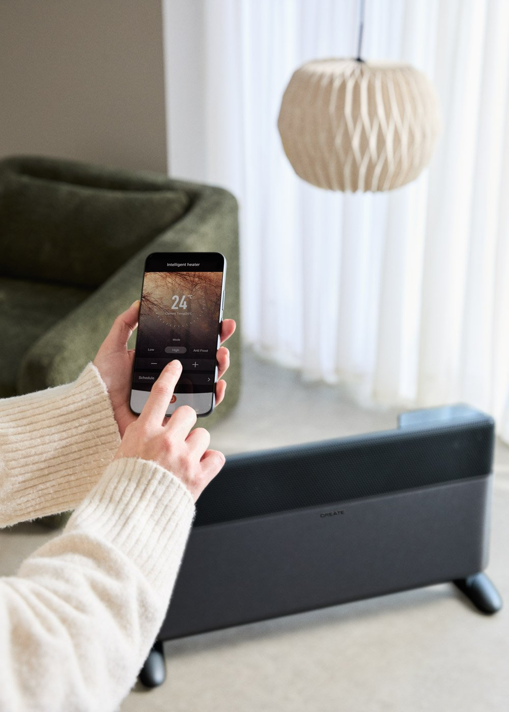 Una persona usa una app de móvil para controlar un calefactor de 24 grados.