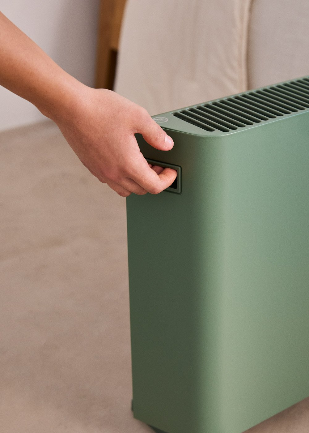 Una mano maneja un ventilador verde con asa.