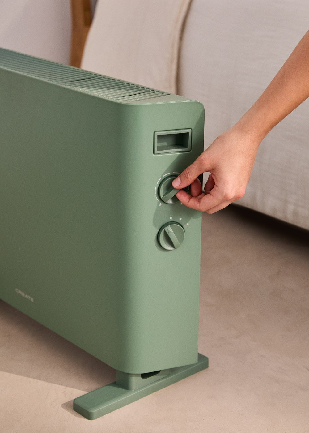 Radiador verde con diales de control operados por una mano.