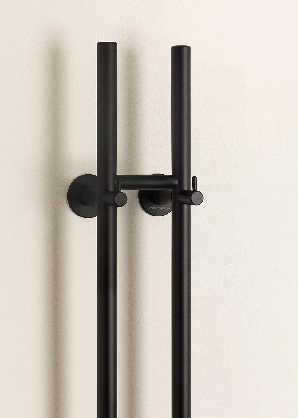 Soporte de ducha negro con dos barras verticales montadas en pared crema.