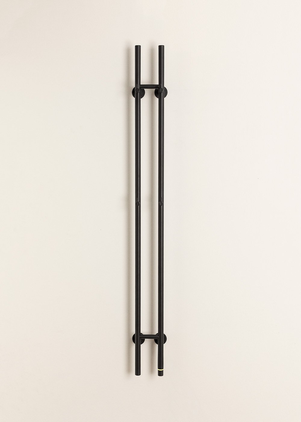 Un tirador de puerta vertical negro en forma de H montado en una pared color crema.