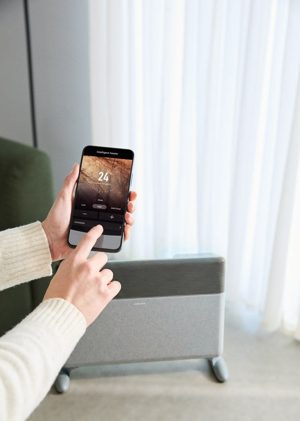 Una persona usa un smartphone con una app de control de calefacción junto a un radiador.