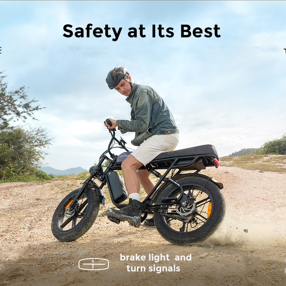 Mężczyzna jedzie rowerem elektrycznym po piaszczystej drodze, w kasku i kurtce.