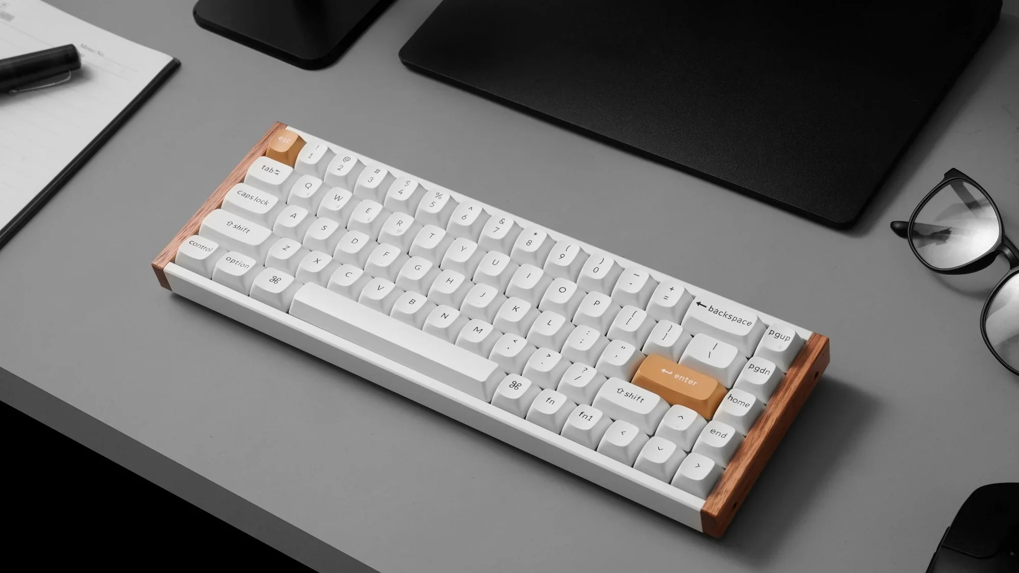 Biała klawiatura z drewnianymi akcentami na szarym biurku.