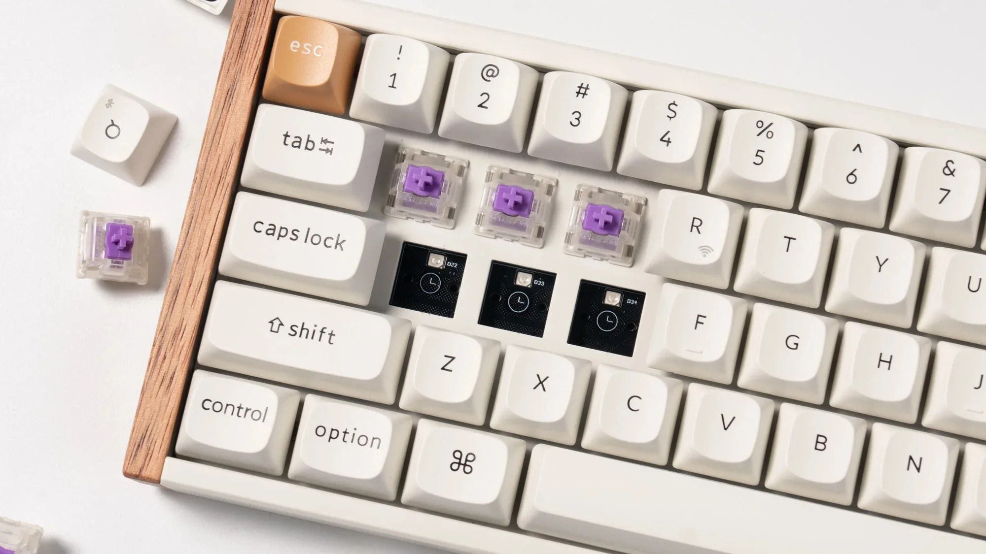 Biała klawiatura z fioletowymi przełącznikami i drewnianą ramką, brakuje klawiszy.