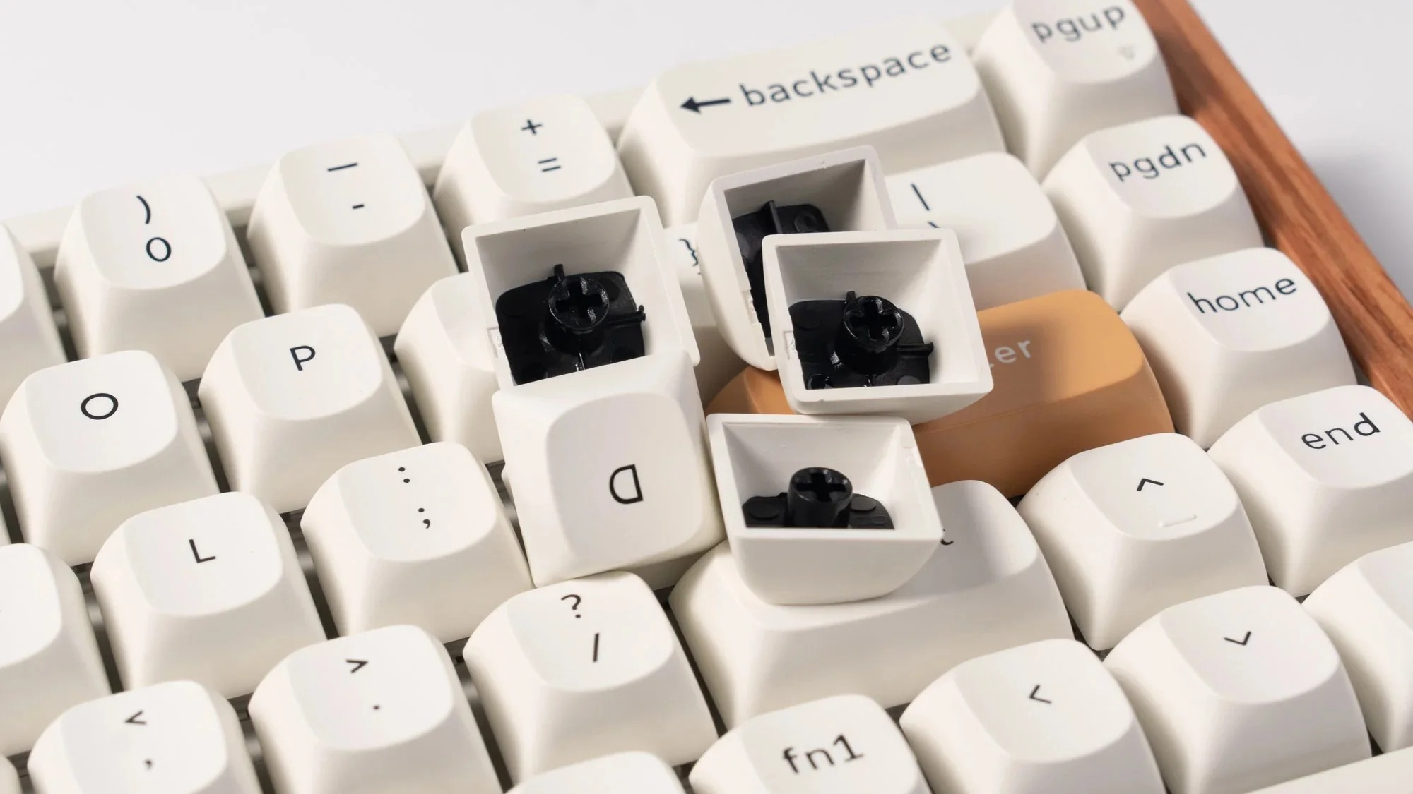 Biała klawiatura mechaniczna z trzema usuniętymi klawiszami, pokazująca czarne przełączniki.