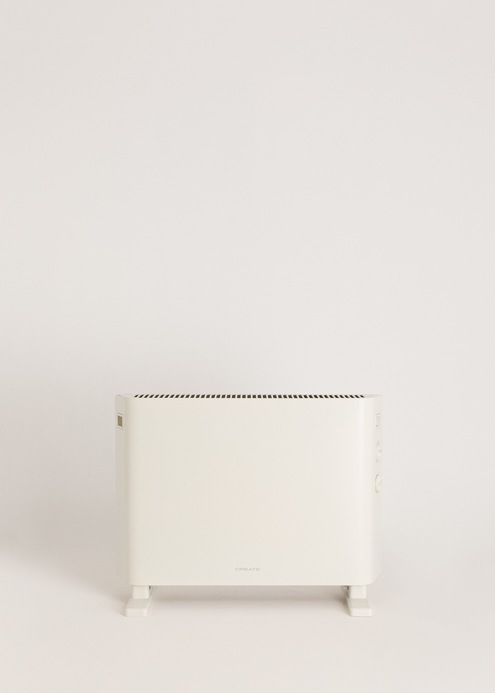 Un radiador blanco con ranuras de ventilación y controles sobre fondo claro.