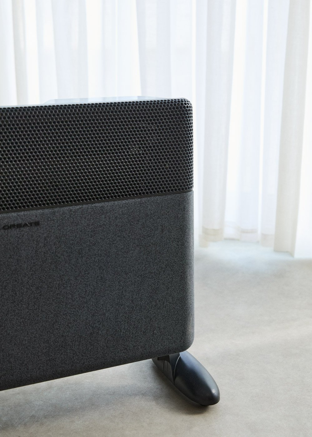 Un altavoz rectangular oscuro con cubierta de tela y rejilla perforada.