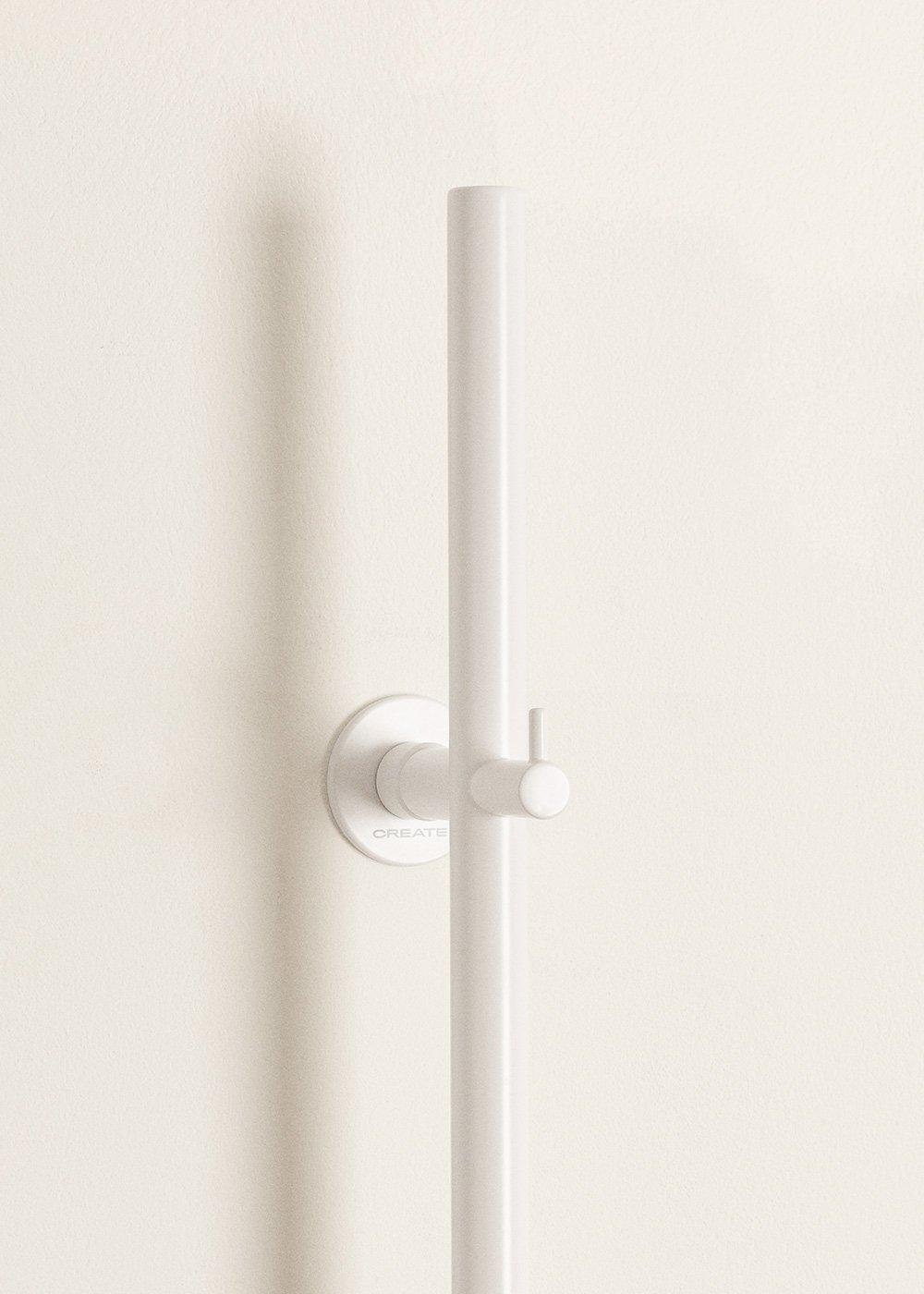 Un soporte de ducha blanco en una pared color crema con la palabra 