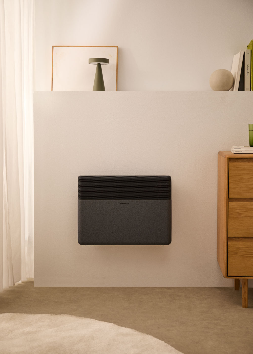Un calefactor oscuro cuelga en una pared blanca junto a un mueble de madera.
