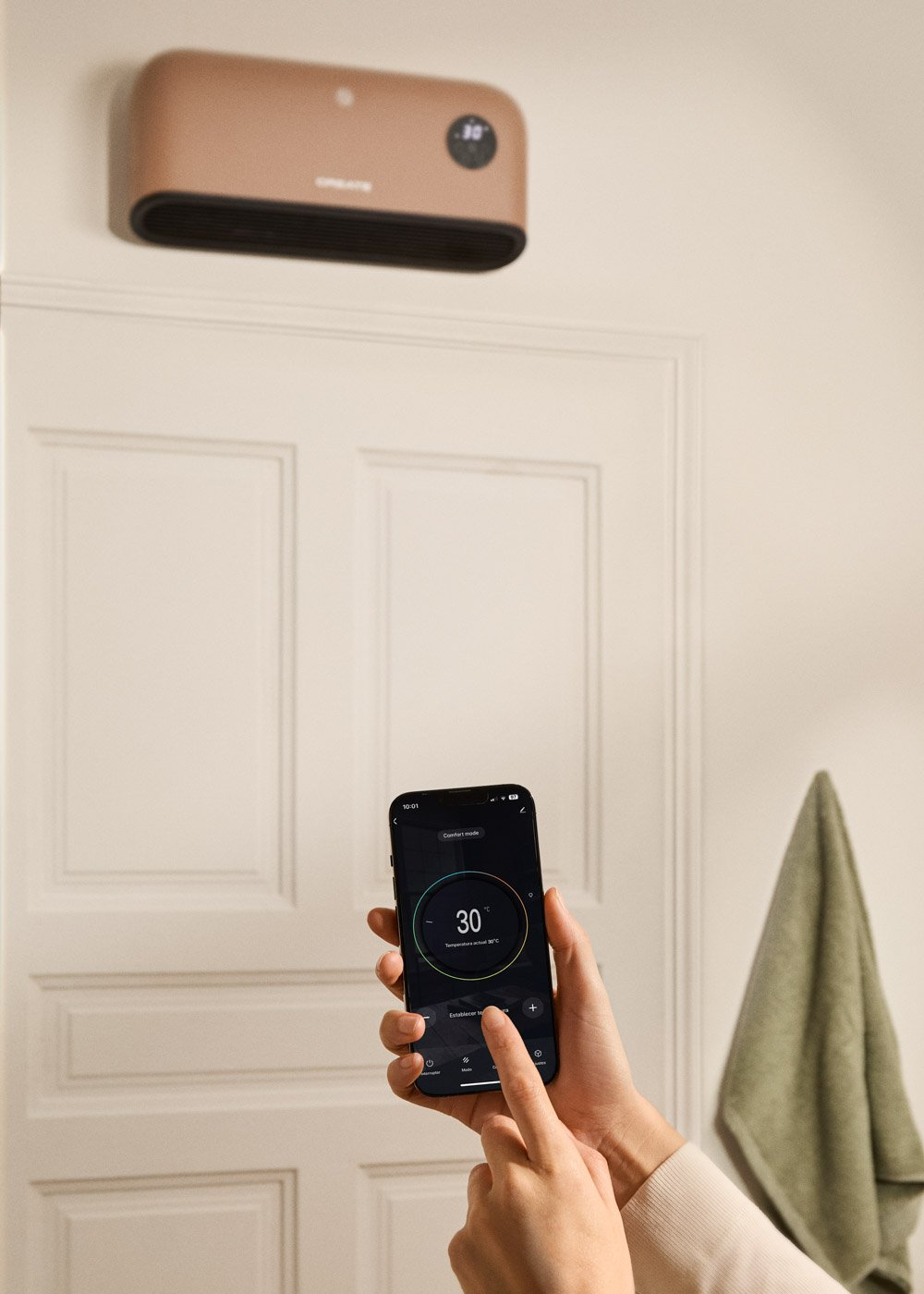Un smartphone controla un calefactor de pared. Una puerta está cerrada al fondo.