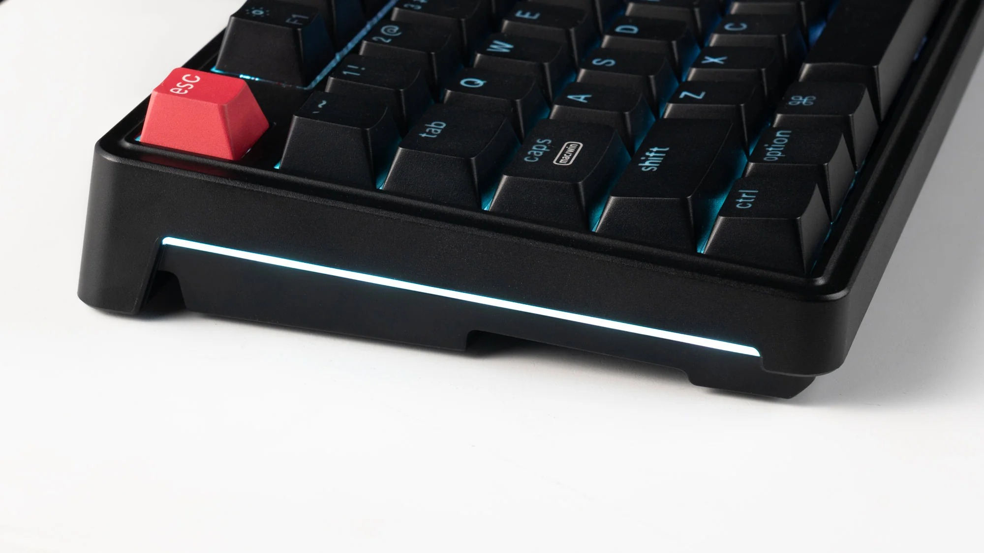 Zbliżenie czarnej klawiatury z czerwoną klawiszem ESC i niebieskim podświetleniem.