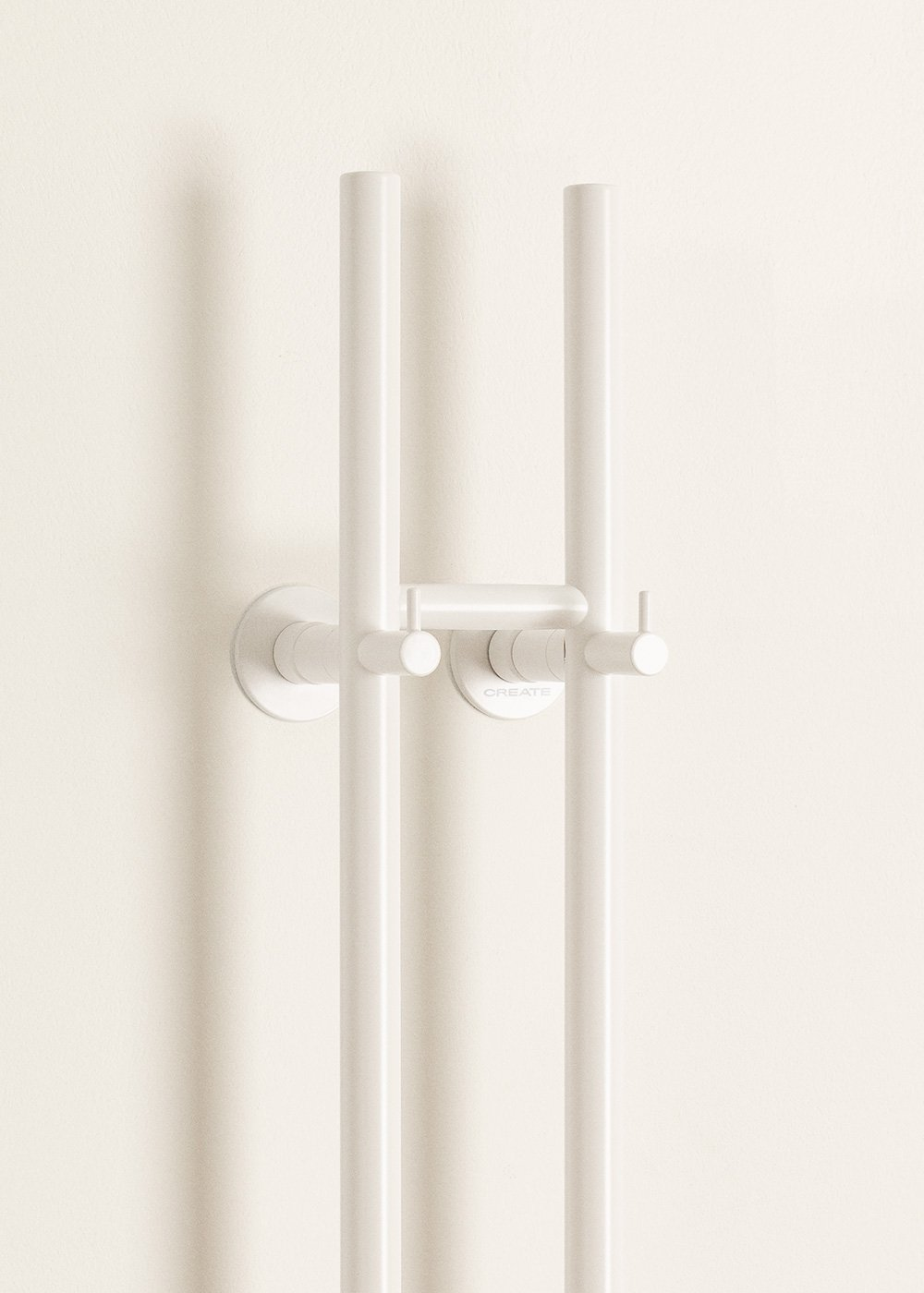 Un soporte blanco para alcachofa de ducha en una pared color crema.