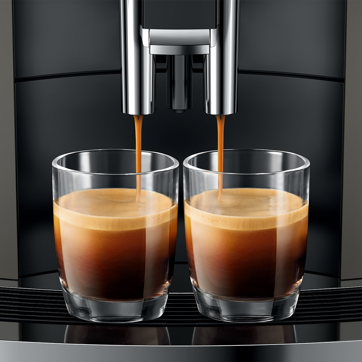 Dwa szklanki espresso przygotowywane przez ekspres do kawy.