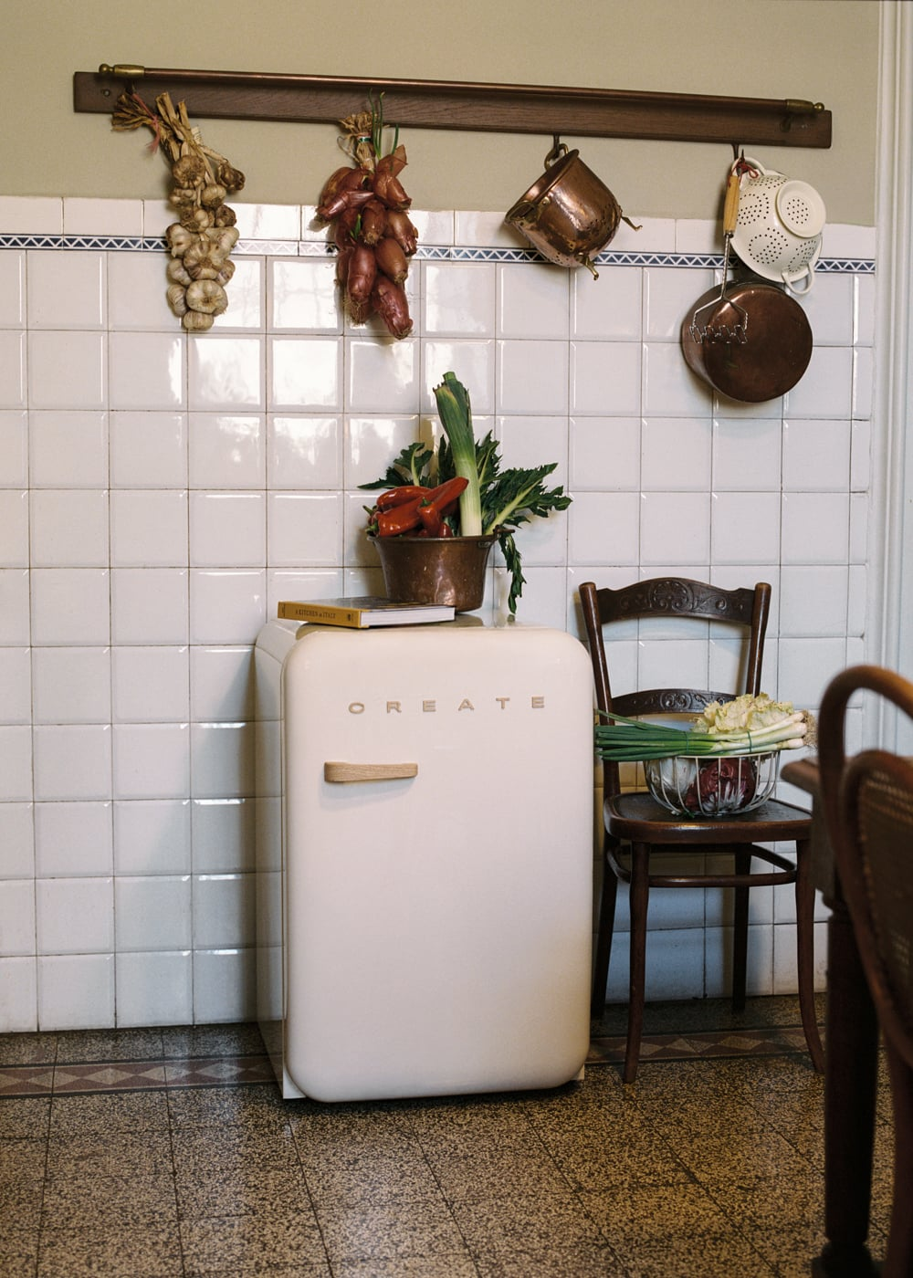 Un refrigerador blanco con verduras y utensilios de cocina en una cocina.