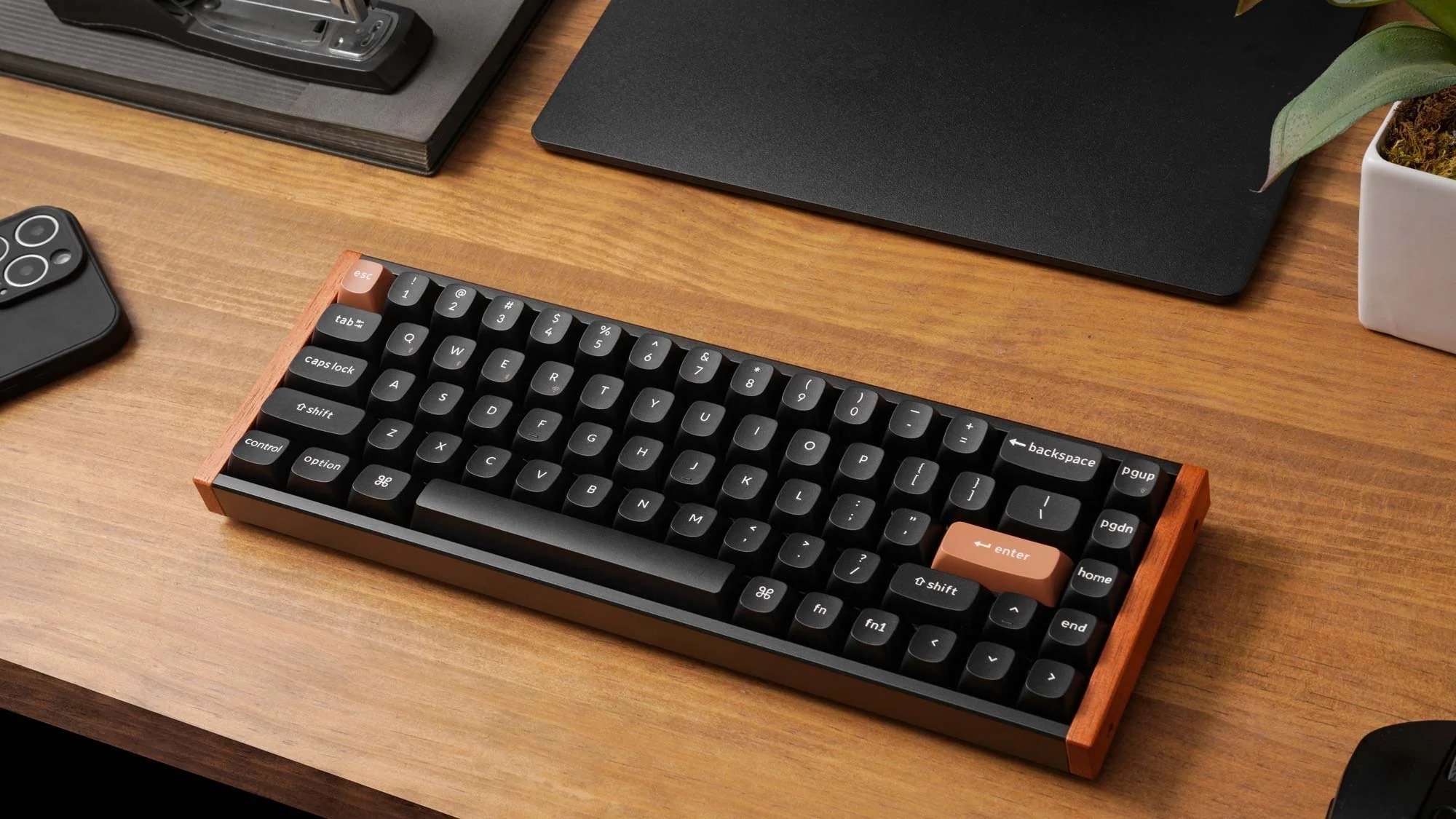 Czarna klawiatura mechaniczna z drewnianą ramką stoi na drewnianym biurku.
