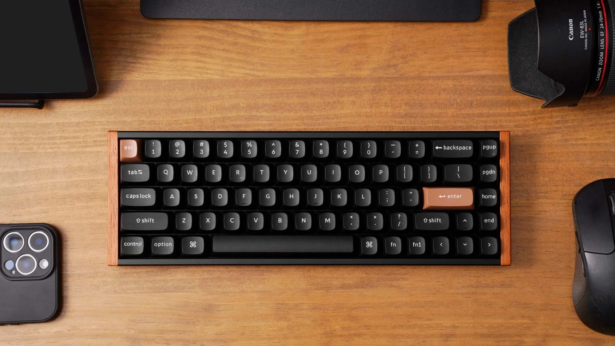 Czarna klawiatura z drewnianą ramką, obok iPhone'a, obiektywu aparatu i myszy.