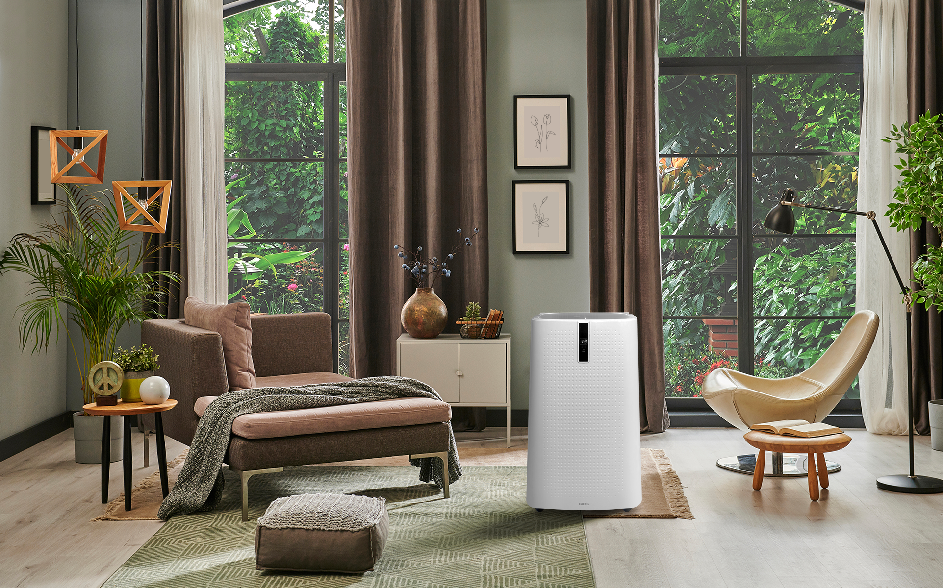 Biały oczyszczacz powietrza stoi obok beżowego fotela w salonie z dużymi oknami.