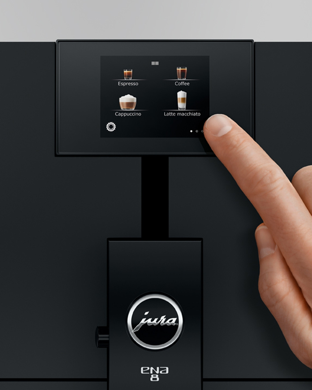Una mano tocca lo schermo di una macchina da caffè con opzioni di bevande.