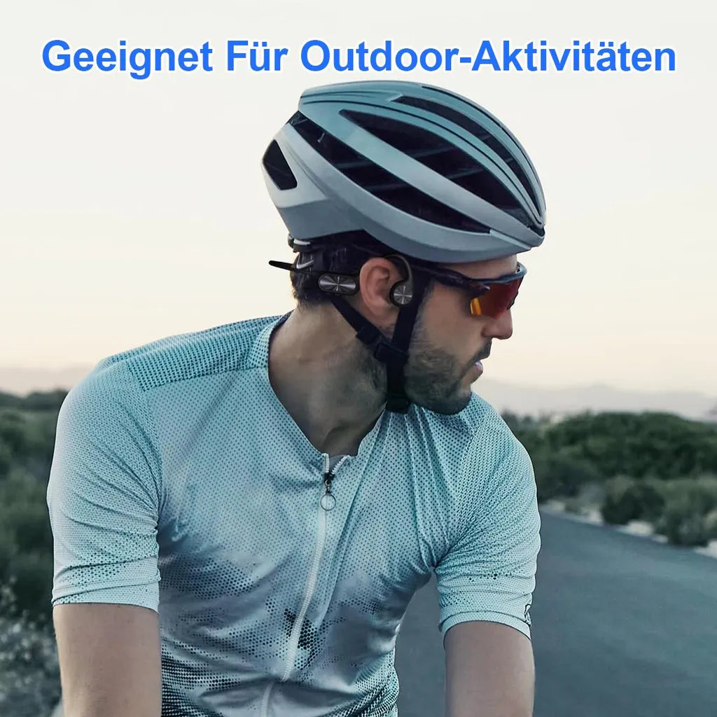 Mann mit Helm und Brille fährt Fahrrad auf Straße, Himmel im Hintergrund.